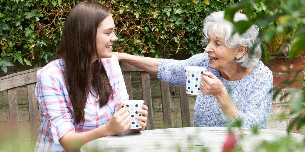 grandmother and granddaughter having tea in garden